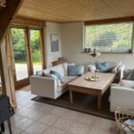 Living room with sofa, table, and windows. Wooden ceiling and terrace door.