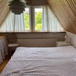 Bedroom with sloped ceiling, window, bed, and desk.