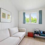 Living room with white sofa, window with blue curtains, and wooden floor.