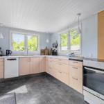 Kitchen with light cabinets, windows, and modern equipment.