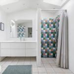 Bathroom with shower, sink and toilet. Walls tiled with colorful squares.