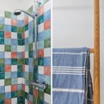 Shower area with colorful tiles and wooden towel rack with blue towel.