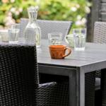 Outdoor area with table, chairs, and drinks. Background with flowers.