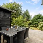 Terrace with table and chairs, view of green garden with flowers.