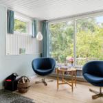 Room with fireplace, two blue chairs, and large window with view.