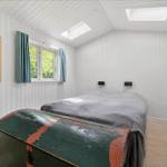 Bedroom with bed, window, skylights, and old trunk.