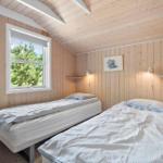 Zwei Einzelbetten in einem Holzraum mit Fenster und Wandlampen.
