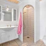 Badezimmer mit Dusche, Waschbecken und Toilette. Ein rosa Handtuch hängt an der Wand.