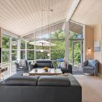 Wohnzimmer mit großem Fenster, Sofa, Fernseher und Blick auf Garten.