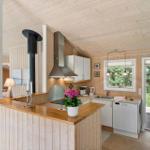 Küche mit Holzvertäfelung, Arbeitsplatte und Fenster zur Außenterrasse.