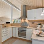 Küche mit Holzwand, weißen Schränken und Edelstahlherd.