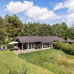 Moderne Ferienhaus mit Terrasse, Garten und Blick auf Wald.
