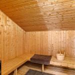 Sauna mit Holzwandverkleidung, Sitzbank und Holzwanne mit Besen.