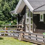 Holzterrasse mit Tisch, Gartenmöbeln und Pflanzen vor einem Haus mit dunkler Fassade.