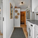 Flur mit Waschmaschine, Sauna und Schlafzimmer. Weiße Wände, Holzboden und Küchengeräte.