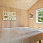 Schlafzimmer mit Holzwandverkleidung, Bett und Fenster mit Blick auf Grün.