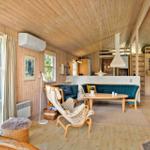Wohnraum mit Holzdecke, blauem Sofa und Holzmöbeln. Fenster und Balkon sichtbar.