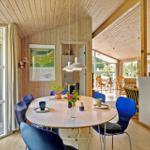 Essbereich mit runden Tisch und blauen Stühlen, Holzwände und große Fenster.