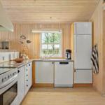 Küche mit Holzwand, Kühlschrank, Spüle und Fenster.