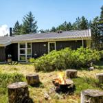 Ein Haus mit Garten und Feuerkorb. Im Hintergrund sind Bäume zu sehen.