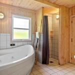 Bad mit Whirlpool, Dusche und Waschbecken. Holzwände und Fenster mit Blick.