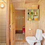 Bad mit Dusche, Toilette und Waschbecken. Sauna im Hintergrund.