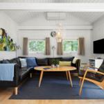 Ein Wohnzimmer mit schwarzer Sofa, Holztisch und Fernseher an der Wand.