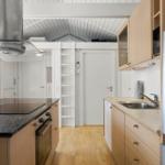 Küche mit Holzschrank, Spüle, Herd und Dunstabzug.