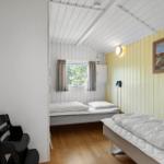 Zimmer mit zwei Betten, Fenster, Wandbild und Holzboden.