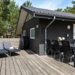 Terrasse mit Tisch, Stühlen und Liegen vor einem Holzhaus.