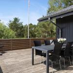 Terrasse mit Tisch und Stühlen, Holzgeländer und Blick auf Bäume.