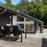 Terrasse mit Tisch und Stühlen vor einem Haus mit großem Fenster.