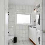 Badezimmer mit Toilette, Waschmaschine und Fenster