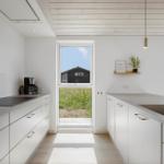 Küche mit weißen Schränken, Steinarbeitsplatte und Fensterblick auf Grünfläche.