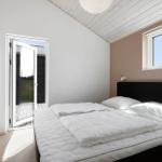 Schlafzimmer mit weißem Bett, Fenster und Tür zum Außenbereich.