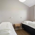 Zwei Betten mit weißen Bettwäsche, Nachttisch und Fenster mit Pflanze.