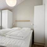 Schlafzimmer mit weißem Bett, Fenster und Schränken.