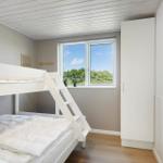 Ein Schlafzimmer mit Doppelstockbett, Fenster und Schrank.