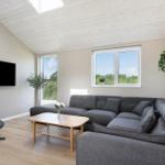 Wohnzimmer mit grauem Sofa, Holztisch und TV an der Wand.