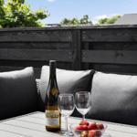 Auf der Terrasse steht ein Tisch mit Wein, Gläsern und einer Schale Erdbeeren.