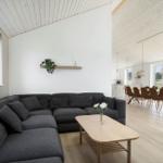 Wohn- und Essbereich mit grauem Sofa, Holztisch und Lichtdurchflutung.