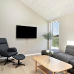 Wohnzimmer mit Sofa, Sessel, Fernseher und Holztisch.