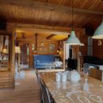 Esszimmer mit Holzwand und Tisch, Wohnzimmer mit Sofa und Kamin im Hintergrund.