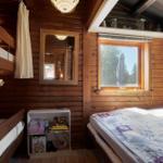 Zimmer mit Holzwand, Doppelbett, Schlafcouch und Fenster mit Blick.