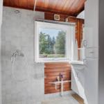Badezimmer mit Dusche, Waschbecken und Fenster zum Wald