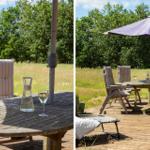 Terrasse mit Tisch, Stühlen und Sonnenschirm. Hintergrund: Grasland und Bäume.