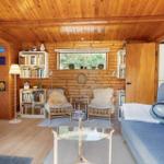 Wohnzimmer mit Holzwand, Sofa, Stühlen und Bücherregalen.