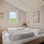 Schlafzimmer mit Holzwand, Bett und Fenster mit Blick auf Gras.