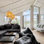 Wohnzimmer mit Sofa, Couchtisch und großen Fenstern. Holzdecke und -wände.