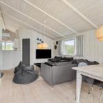 Wohn- und Essbereich mit Sofa, Esstisch und Kaminofen. Holzwände und Decke.